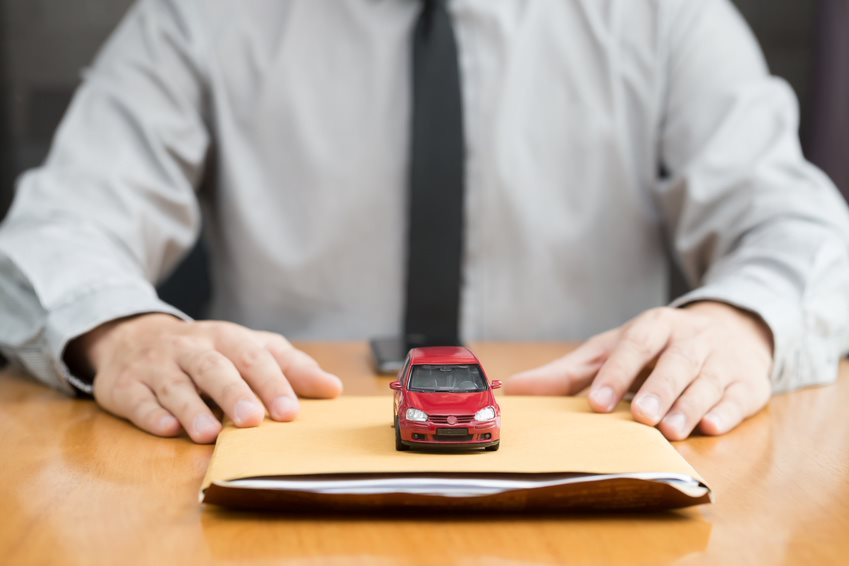 Man in a tie with a manila folder and red toy car